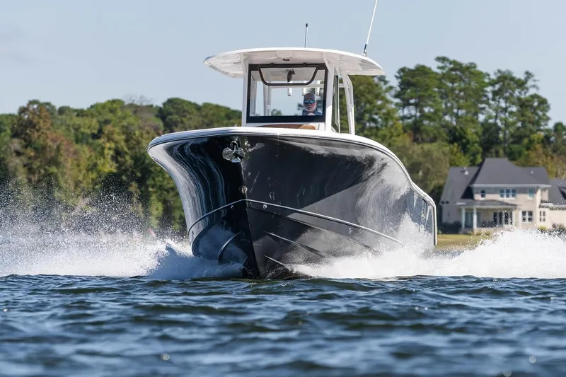 The Image of 2026 Sea Hunt Ultra 285 SE cruising on water near a lakeside house. - 0
