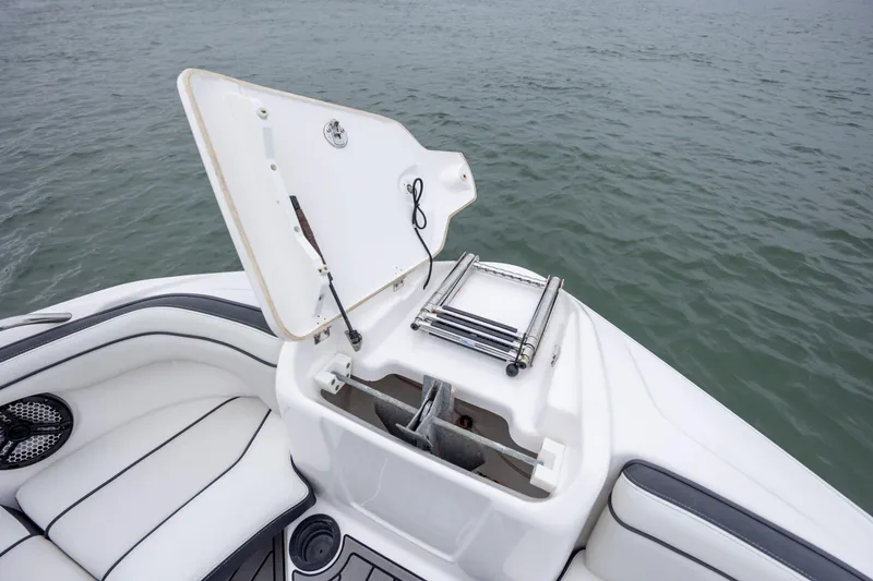 Slide: The Image of 2017 Yamaha Boats SX210 with open storage compartment and ladder on calm water. - 13