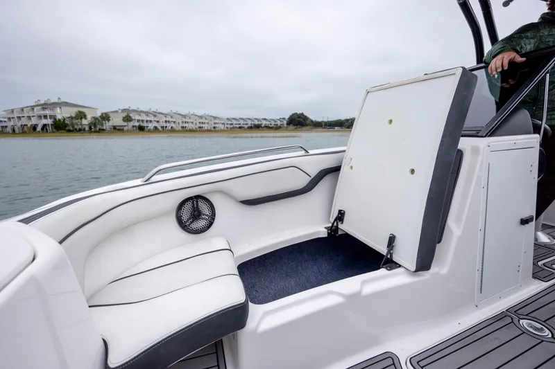 Slide: The Image of 2017 Yamaha SX210 boat interior with seating and storage, near waterfront homes. - 16