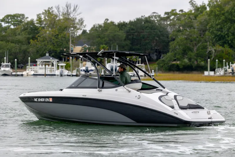 Slide: The Image of 2017 Yamaha Boats SX210 cruising on a scenic waterway with lush greenery. - 2
