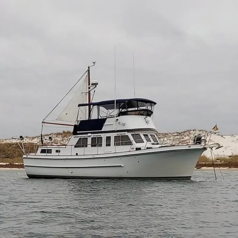 The Image of 1976 Cheoy Lee 40 LRC yacht anchored near sandy shoreline under cloudy sky. - 0