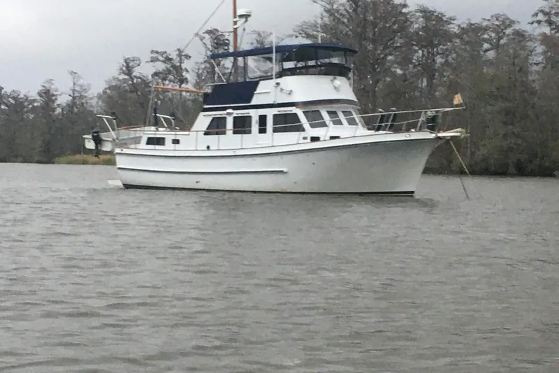 Slide: The Image of 1976 Cheoy Lee 40 LRC yacht anchored on a calm river with trees in the background. - 2