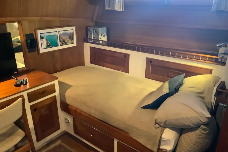 Slide: The Image of 1976 Cheoy Lee 40 LRC cabin with cozy bed, wooden decor, and framed pictures. - 42