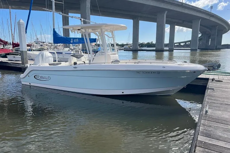 The Image of 2022 Robalo R242 Center Console boat docked near a bridge in a marina. - 0