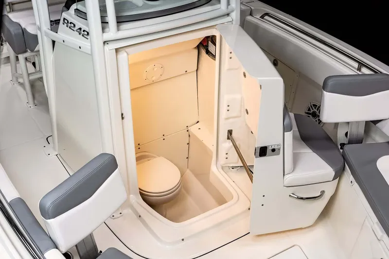 Slide: The Image of Manufacturer Provided Image: 2022 Robalo R242 Center Console boat interior with open door to marine toilet. - 3