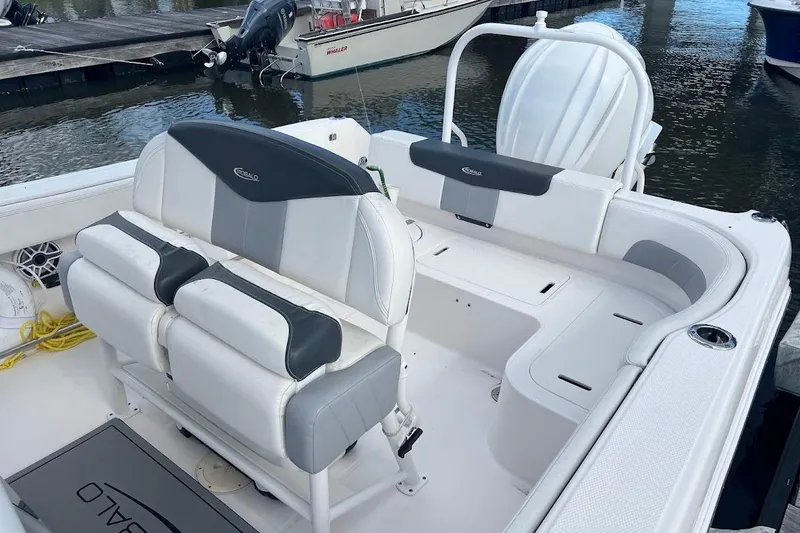 Slide: The Image of 2022 Robalo R242 Center Console boat interior with seating and storage, docked by the water. - 4