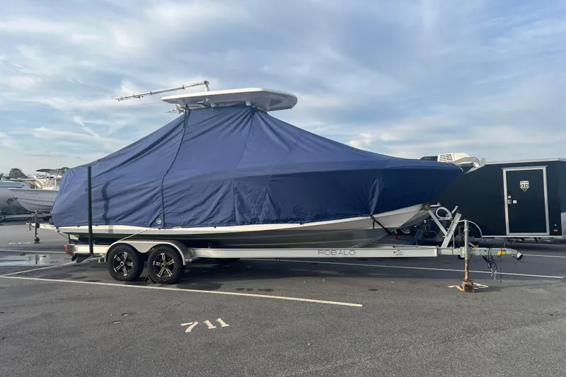 Slide: The Image of 2022 Robalo R242 Center Console boat covered on trailer in parking lot. - 7