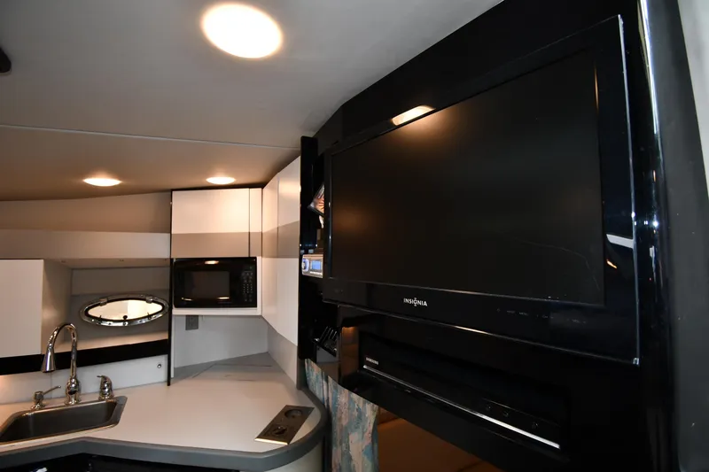 Slide: The Image of 1990 Formula interior with modern kitchen, sink, microwave, and large Insignia TV. - 31