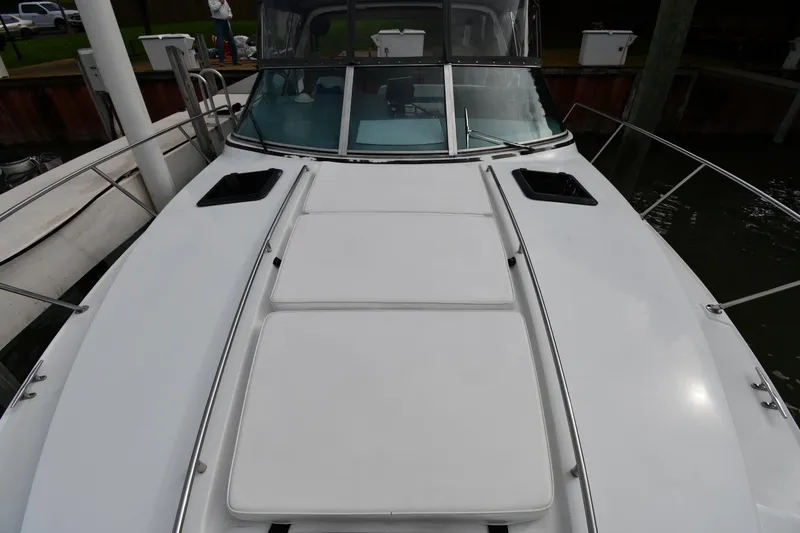 Slide: The Image of 1990 Formula boat deck with white cushions and windshield, docked at marina. - 6