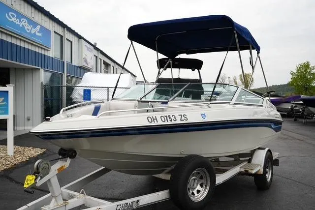 The Image of 1992 Celebrity 180 Bowrider boat on trailer, parked outside a marine dealership. - 1