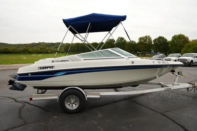 Slide: The Image of 1992 Celebrity 180 Bowrider boat on trailer with blue canopy, parked outdoors. - 3