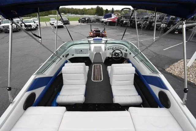 Slide: The Image of 1992 Celebrity 180 Bowrider boat with white seating and blue accents in a parking lot. - 7