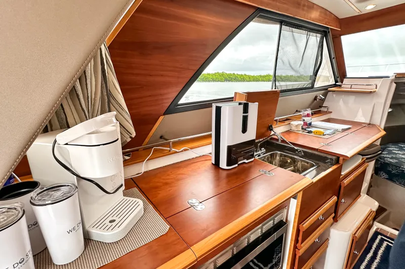 Slide: The Image of 2022 Cutwater 30 Command Bridge interior with kitchenette, featuring wood finish and modern appliances. - 15