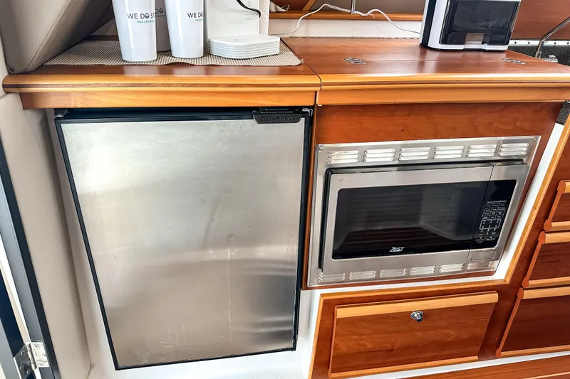 Slide: The Image of 2022 Cutwater 30 Command Bridge galley with stainless steel fridge and microwave. - 25