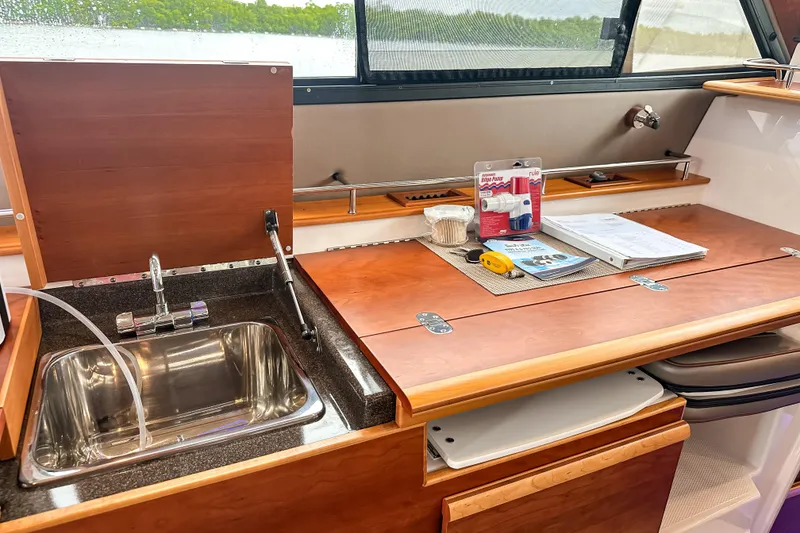 Slide: The Image of 2022 Cutwater 30 Command Bridge interior with sink, wooden countertop, and accessories. - 28