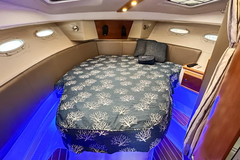 Slide: The Image of 2022 Cutwater 30 Command Bridge cabin with cozy bed, blue lighting, and porthole windows. - 29