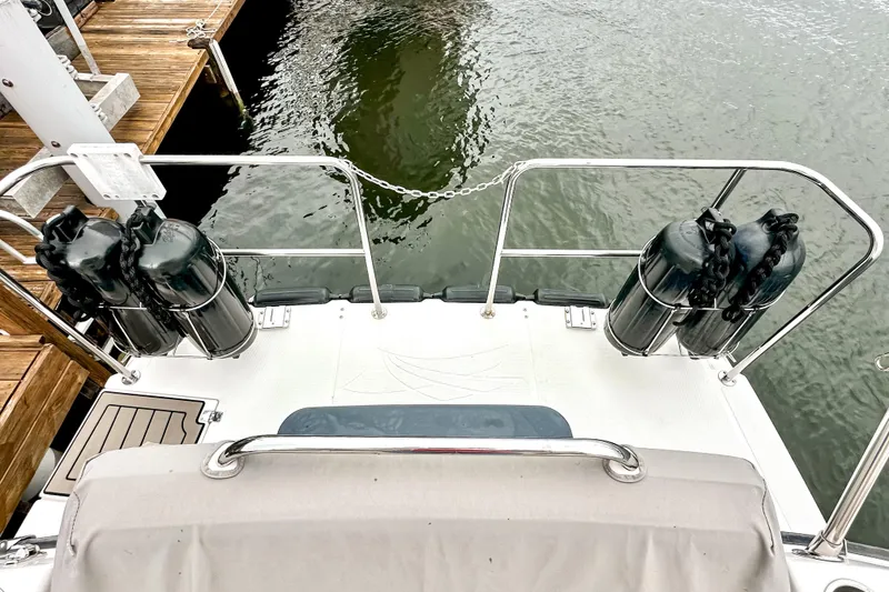 Slide: The Image of 2022 Cutwater 30 Command Bridge boat stern with fenders, docked by wooden pier. - 59