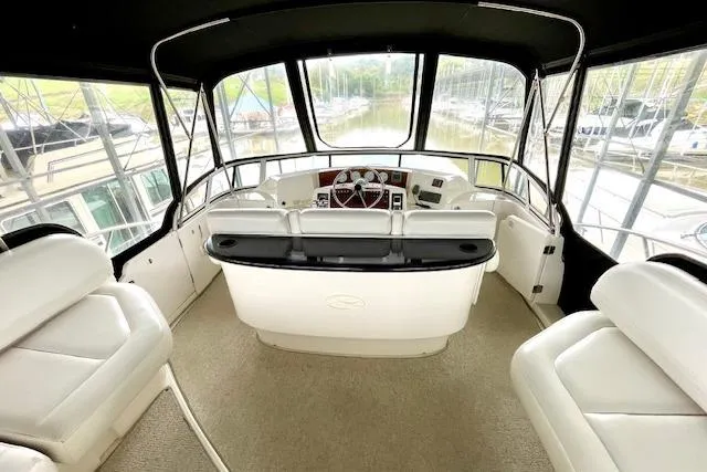 Slide: The Image of 2002 Silverton 43 Motor Yacht helm with white seating and panoramic windows. - 14