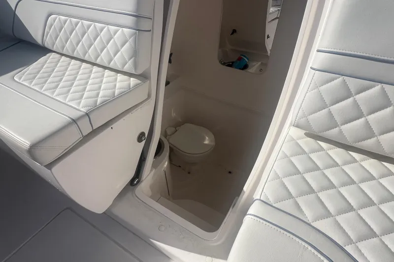Slide: The Image of 2022 Intrepid 327-I CC boat interior with white quilted seating and compact restroom. - 20