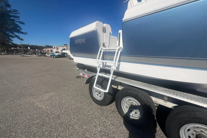 Slide: The Image of 2022 Intrepid 327-I CC boat on trailer, parked outdoors under clear blue sky. - 43