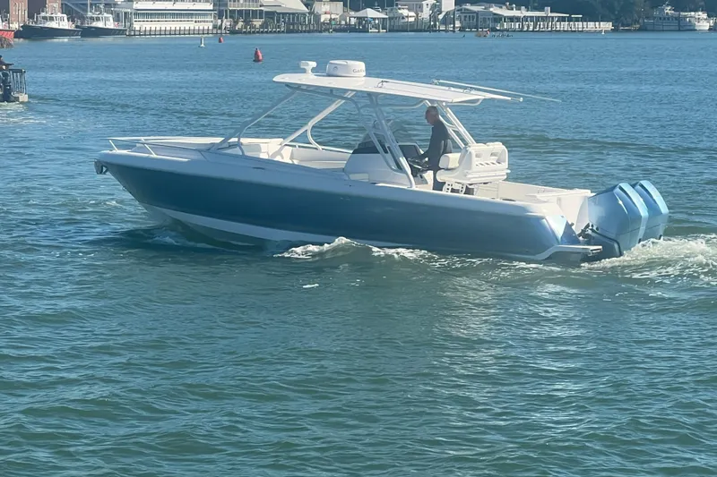 Slide: The Image of 2022 Intrepid 327-I CC boat cruising on calm waters near a marina. - 60