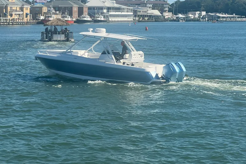 Slide: The Image of 2022 Intrepid 327-I CC boat cruising in a scenic harbor setting. - 61