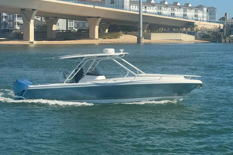 Slide: The Image of 2022 Intrepid 327-I CC boat cruising on water near a bridge and buildings. - 69