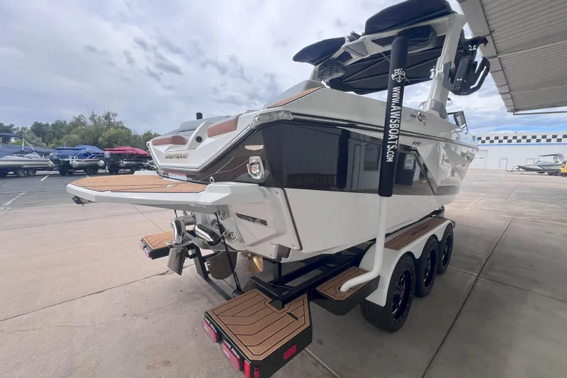 Slide: The Image of 2025 Nautique Super Air Nautique G23 boat on trailer, rear view, in a marina setting. - 5