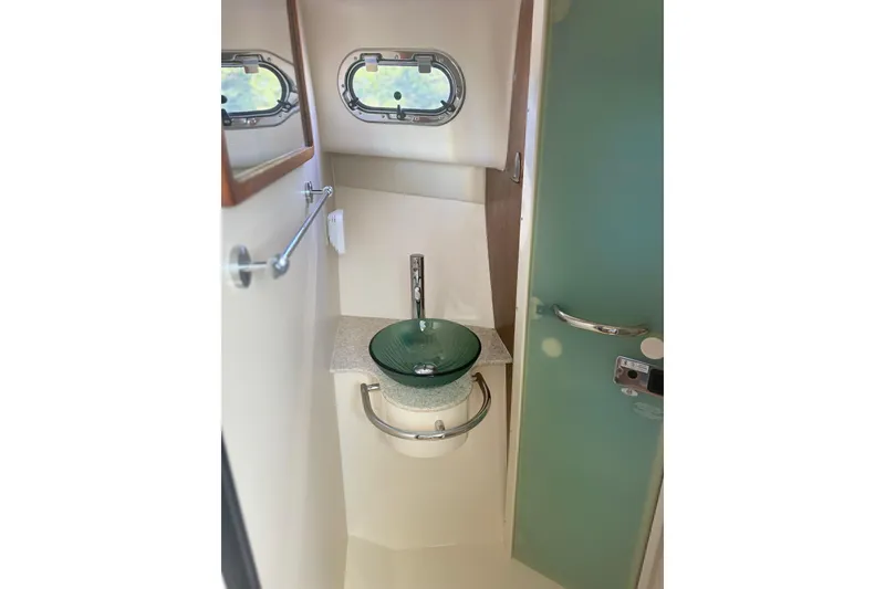 Slide: The Image of Compact bathroom in 2012 Pursuit OS 345 Offshore boat with modern sink and porthole windows. - 23