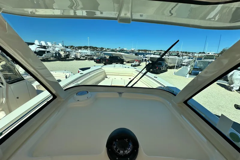 Slide: The Image of 2026 Grady-White Canyon 306 boat interior view at marina, showcasing dashboard and windshield. - 18