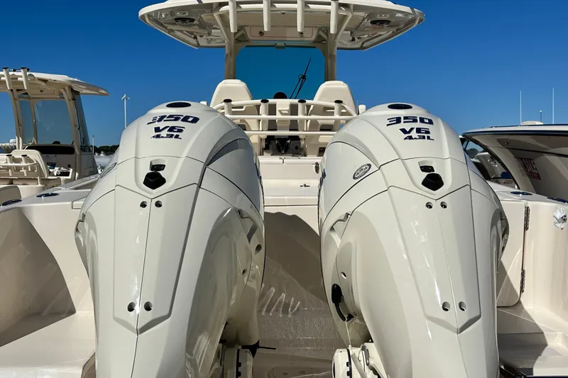 Slide: The Image of 2026 Grady-White Canyon 306 boat with twin 350 V6 engines, docked under clear blue sky. - 8