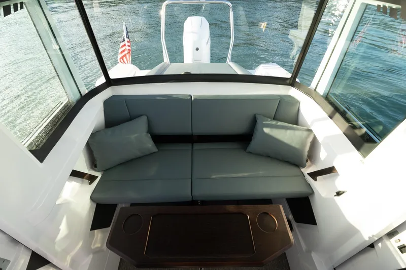 Slide: The Image of 2026 Axopar 29 XC Cross Cabin interior with cushioned seating and table, overlooking water. - 35