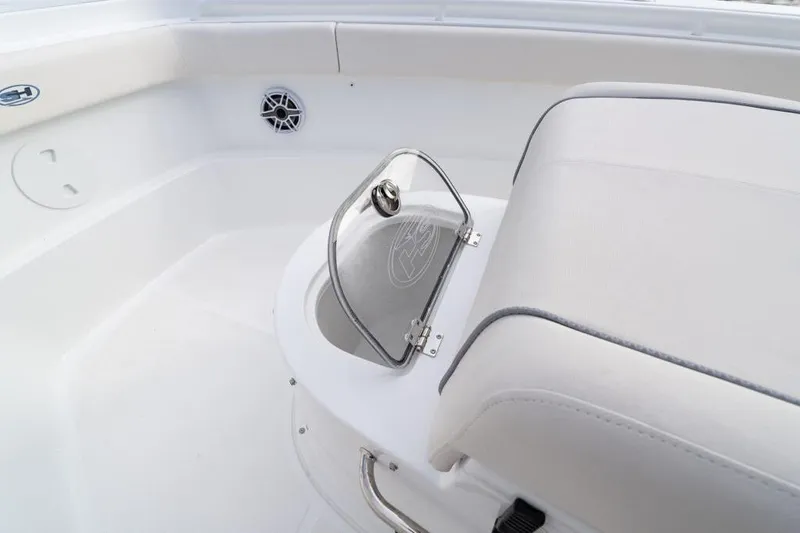 Slide: The Image of 2026 Sea Hunt Ultra 285 Coffin Box boat on a serene lake with lush forest backdrop. - 2