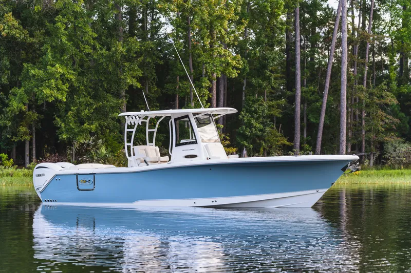 Slide: The Image of 2026 Sea Hunt Ultra 285 Coffin Box boat on calm water, surrounded by lush trees. - 23