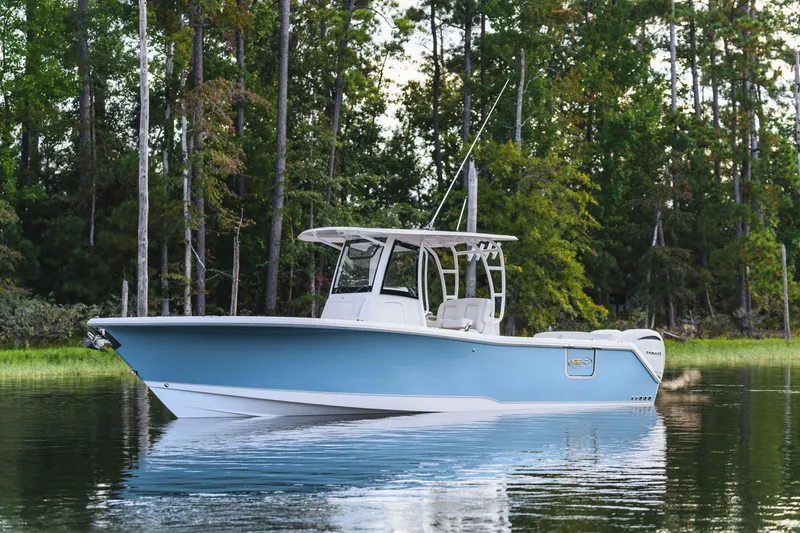 Slide: The Image of 2026 Sea Hunt Ultra 285 Coffin Box boat on calm water, surrounded by lush trees. - 24
