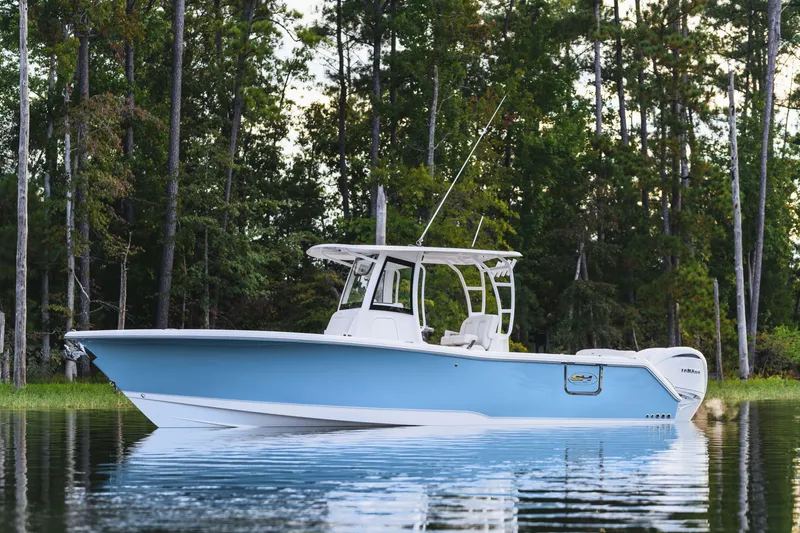 Slide: The Image of 2026 Sea Hunt Ultra 285 Coffin Box boat on calm water, surrounded by trees. - 25