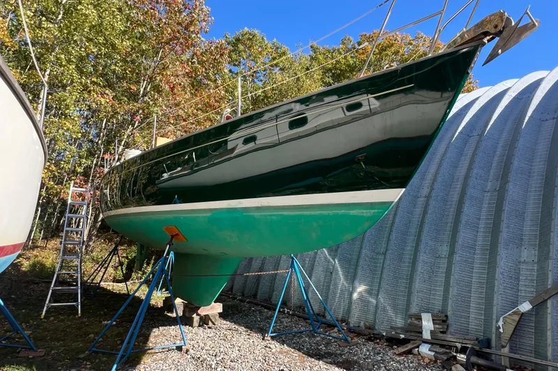 Slide: The Image of 1986 Victoria 34 Sloop sailboat on stands, surrounded by trees and a metal structure. - 1