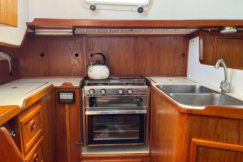 Slide: The Image of 1986 Victoria 34 Sloop kitchen with wooden cabinetry, stove, and sink. - 10