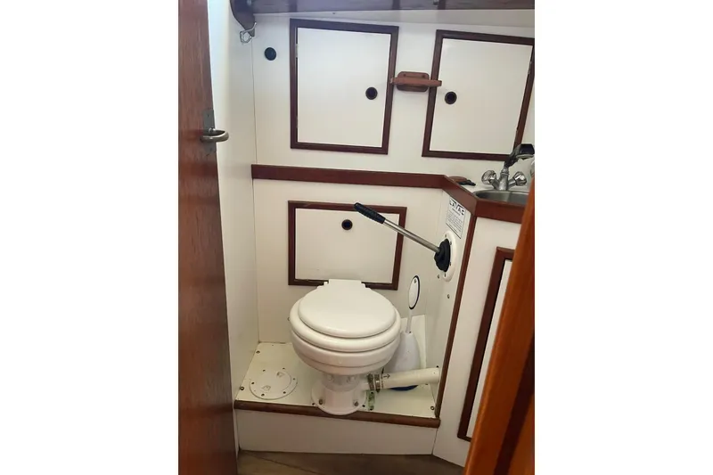 Slide: The Image of 1986 Victoria 34 Sloop bathroom with marine toilet and sink, compact and functional design. - 14