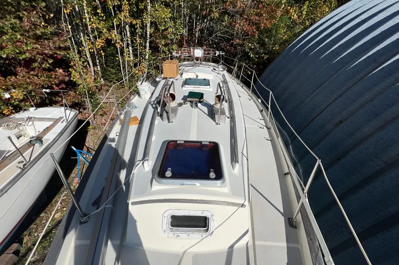 Slide: The Image of 1986 Victoria 34 Sloop sailboat on land, surrounded by trees and a metal structure. - 19
