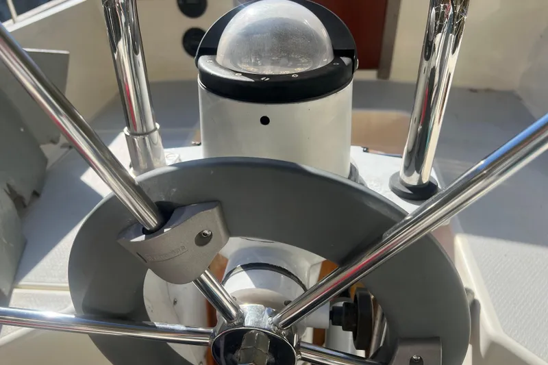 Slide: The Image of Steering wheel of a 1986 Victoria 34 Sloop sailboat, featuring chrome details and compass. - 23