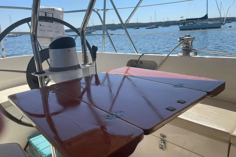 Slide: The Image of Cockpit of 1986 Victoria 34 Sloop with wooden table and steering wheel, overlooking marina. - 26