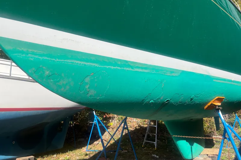 Slide: The Image of Green hull of 1986 Victoria 34 Sloop sailboat on stands, showing wear and maintenance needs. - 34
