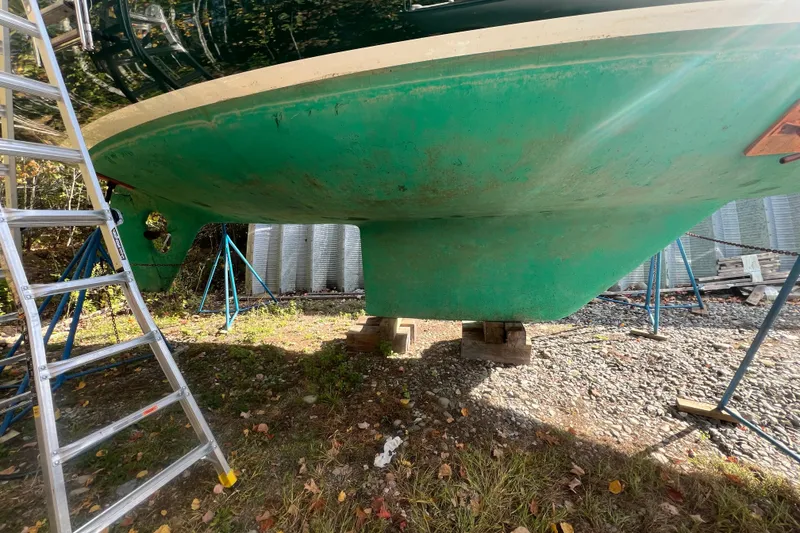 Slide: The Image of 1986 Victoria 34 Sloop sailboat on stands, green hull, ladder nearby. - 46