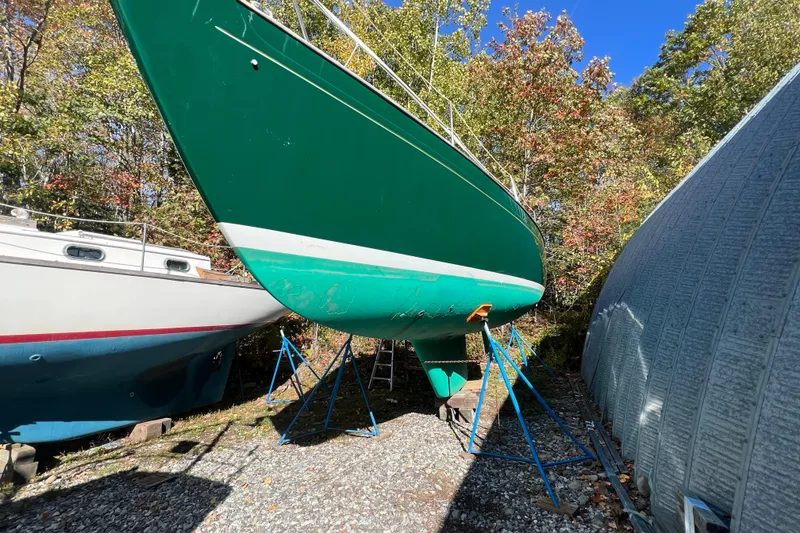 Slide: The Image of Green 1986 Victoria 34 Sloop sailboat on stands, surrounded by trees and blue sky. - 47