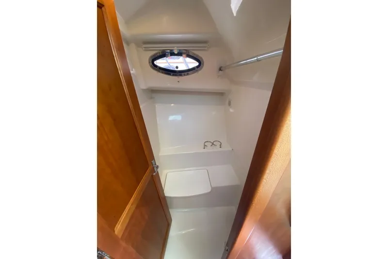 Slide: The Image of 2022 Back Cove 34O yacht interior with white seating and wooden table, docked by the water. - 17