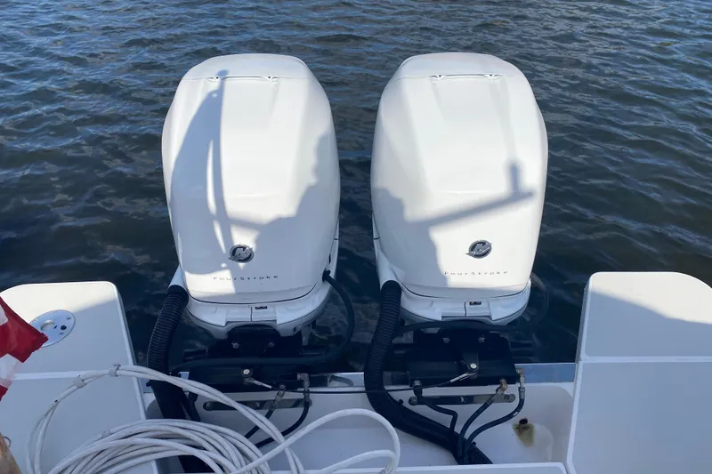 Slide: The Image of 2022 Back Cove 34O boat with striped seating, table, and American flag on water. - 27