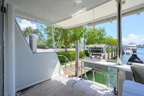 Slide: The Image of 1998 Hatteras 70 Cockpit Motor Yacht docked, featuring spacious deck and outdoor grill. - 12
