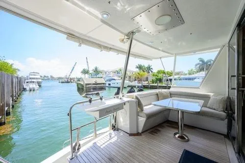 Slide: The Image of 1998 Hatteras 70 Cockpit Motor Yacht with spacious outdoor seating and waterfront view. - 13