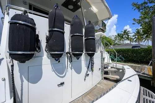Slide: The Image of 1998 Hatteras 70 Cockpit Motor Yacht with fenders, docked under clear blue sky. - 14